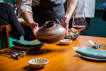 camarero sirve un plato y pan en una mesa de restaurante con copa de vino y platos close-up
