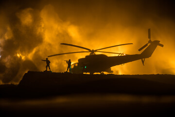 Fototapeta na wymiar Silhouette of military helicopter ready to fly from conflict zone. Decorated night footage with helicopter starting in desert with foggy toned backlit. Selective focus. War concept