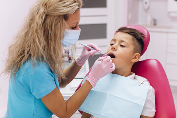 Woman dentist makes a dental examination of the boy mouth