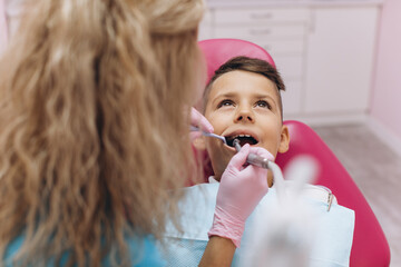 Female dentist treats boy's teeth in dental clinic