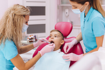Woman dentist makes a dental examination of the boy mouth