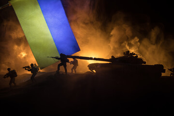 Russian war in Ukraine concept. Silhouette of armed soldiers against Ukrainian flag and burned out...