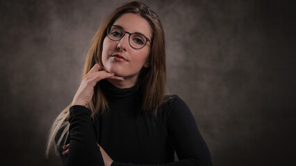 Close-up of a young attractive woman against dark grey background - studio photography
