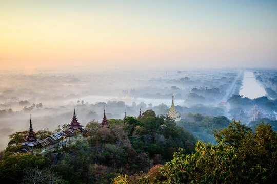 Elevated view of the plain of temples in Mandalay, stupas and spires emerging from the mist, historic Buddhist sites.