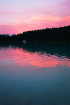Lake Louise with reflections of pink sky at sunset.