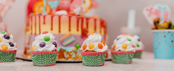 A close-up photo of a birthday cake and muffin on a decorated table.