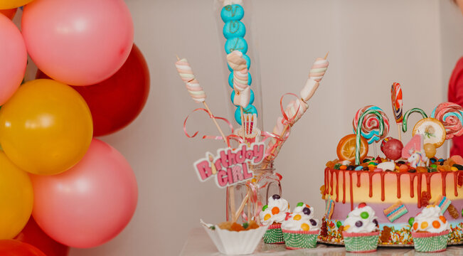 A close-up photo of a birthday cake and muffin on a decorated table.