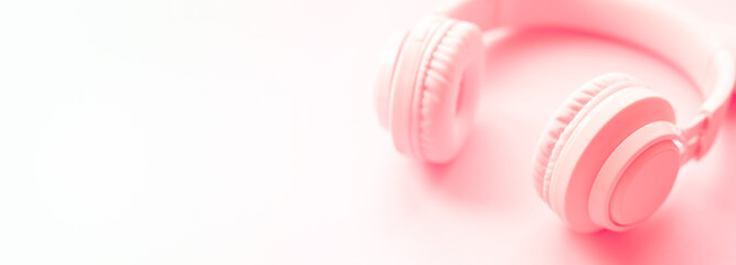 pink headphones on pink background. Minimalist simple photo of earphones with copy space, Closeup banner. Music and New technologies concept. Trendy minimal music device