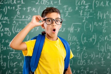 Education concept. Smart boy in glasses standing at the blackboard with formulas