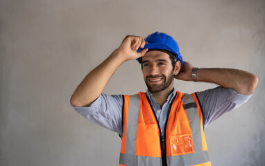 An engineer of Middle Eastern descent smiling,handsome, holding a hard hat,wearing a reflective...