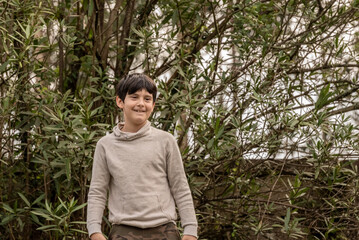 one little boy dance in the forest with his arms down and smiling