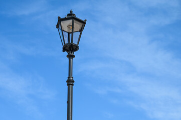 Fototapeta na wymiar Street light against blue sky. Illuminated street light in city. 