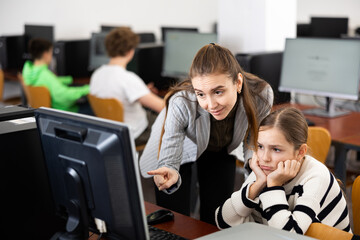 Fototapeta premium Positive woman teacher together with the girl teaches how to work on the computer