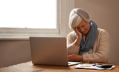 Retirement fund worries.... An elederly woman sitting in front of her laptop looking stressed and worried.