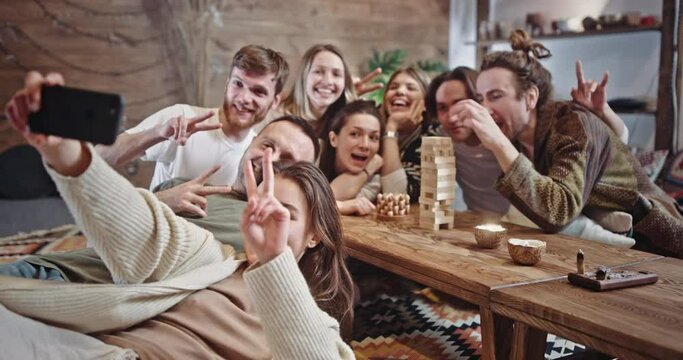 Young hippies taking selfie together. Group of young male and female friends smiling and gesticulating while gathering near table and taking selfie on weekend day.