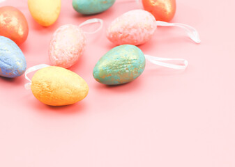 Multi-colored pastel decorative eggs lie in the upper right corner on a light pink