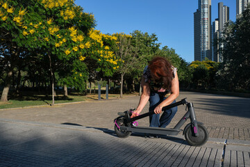 Latin mature woman unfolding her electric kick scooter in the city