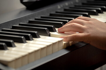 Child's hand presses the piano keys
