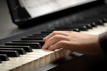 Child's hand presses the piano keys