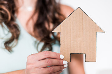 first time home buyers, woman holding cardboard house icon towards the camera
