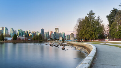 Fototapeta premium Panoramic View of Modern City Building Skyline on West Coast Pacific Ocean. Sunny Winter Sunrise. Seawall at Stanley Park, Coal Harbour, Downtown Vancouver, British Columbia, Canada.