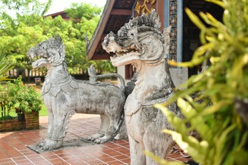 Two lion statues in front of the entrance of main chapel in Wat Nong Bua, Nan Province, THAILAND.