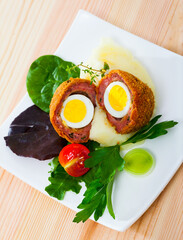 Scotch egg with quail eggs served with mashed potatoes and herbs - traditional English dish