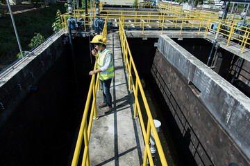 service engineer checking on waste water treatment plant with pump on background. worker working on...