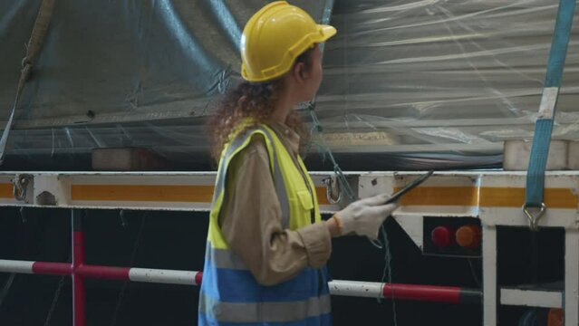 Industrial woman curly hair engineer wear safety uniform with hardhat checking metal sheet on cargo truck before shipment to customer in warehouse store factory workshop, logistics and transportation