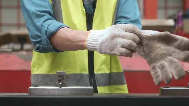 Close up hands of engineer worker man putting gloves on his hand while working in metal sheet factory industry workshop, work male wearing glove