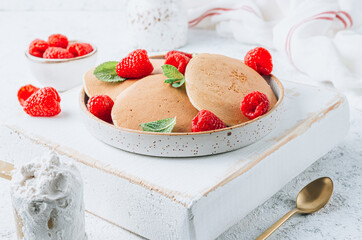 Fresh pancakes for breakfast with raspberry on light background. Summer healthy food
