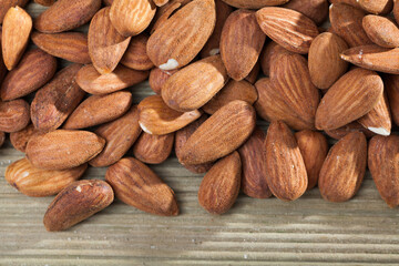 Natural background of shelled roasted almond seeds on light wood surface. Healthy snack