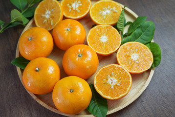 Fresh Tangerine Orange with slices on wooden plate, Mandarin Orange fruit in wooden plate on wooden table in garden	
