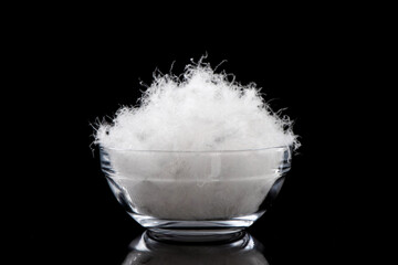 soft fluffy down feather in glass bowl on black background.