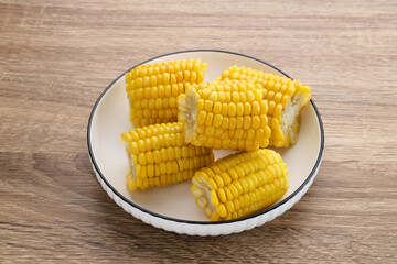 Jagung manis rebus or boiled sweet corn slices served on bowl on wooden background. Space for text. 
