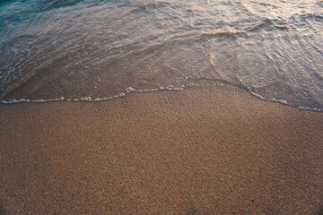 Sea wave on sandy beach morning sun light