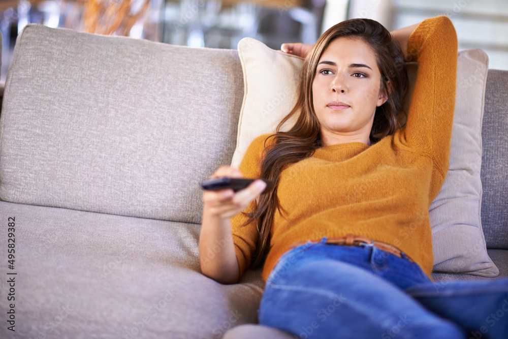 Poster Channel surfing is all Im doing today.... Cropped shot of an attractive young woman changing TV channels with the remote.