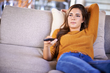 Channel surfing is all Im doing today.... Cropped shot of an attractive young woman changing TV channels with the remote. © Yuri A for PeopleImages/peopleimages.com