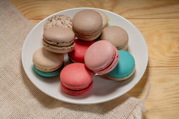 Close up macaron dessert pastel tones on white plate , Sweet and colorful french macaroons  on wooden background, Dessert.