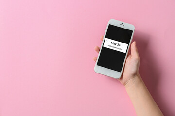 Hand holding phone with text MAY 21. NATIONAL MEMO DAY on screen against pink background