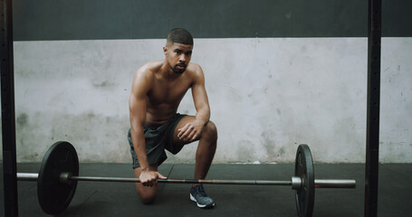 Fototapeta na wymiar When faced with a challenge, dont run for the exit. Portrait of a muscular young man exercising with a barbell in a gym.