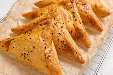 Cooling rack with tasty Uzbek samsa on white background, closeup