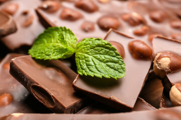 Pieces of tasty chocolate with nuts and mint, closeup