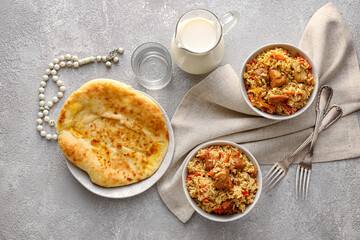 Bowls of tasty Asian pilaf and flatbread on grunge background