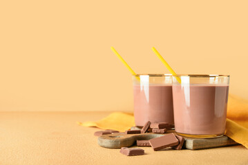 Glasses of delicious chocolate milk on color background