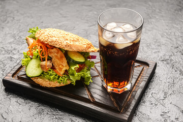 Fresh doner kebab in bun with glass of cola drink on dark background