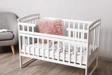 Comfortable crib near light wall in children's room