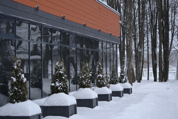The exterior of a commercial building with large windows in the snowdrifts in winter. The windows...