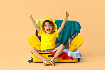 Little boy with suitcase and belongings on color background © Pixel-Shot