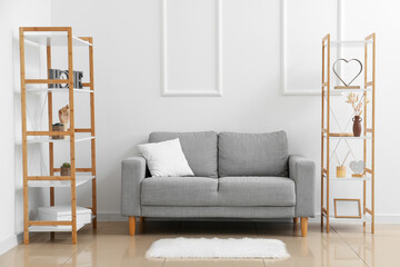 Comfy grey couch with shelving units near white wall